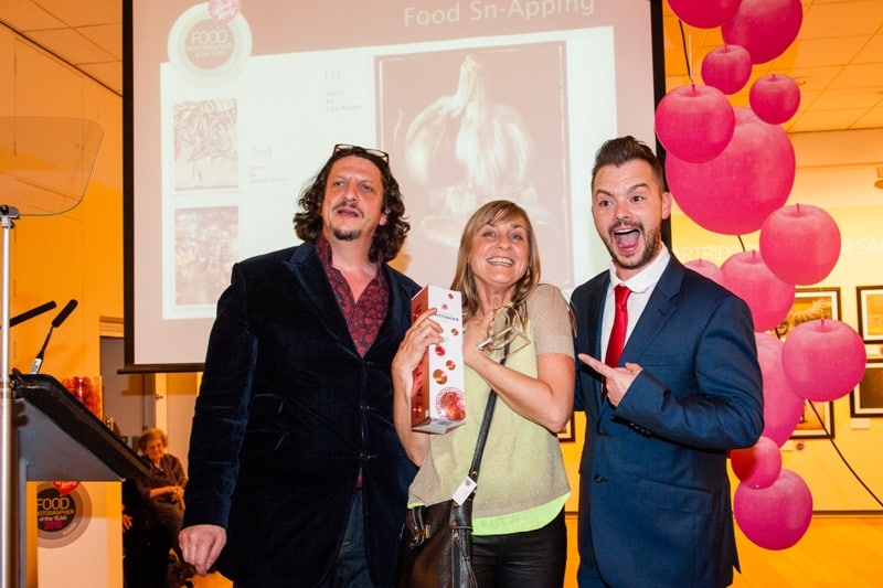 Three people smiling and holding an award