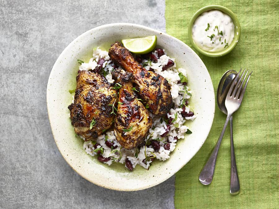 a plate of jerk chicken and rice on a white and green table cloth